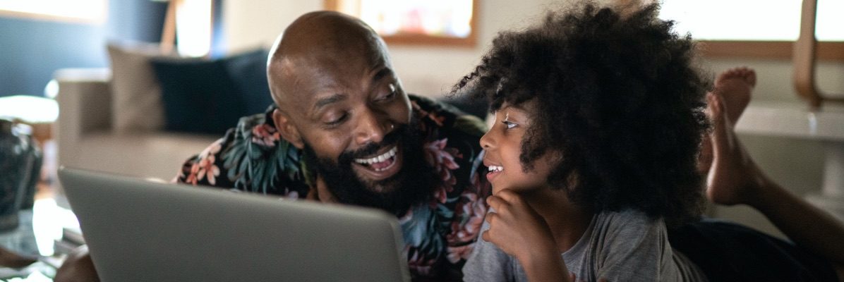Man and woman laugh while sitting at a laptop