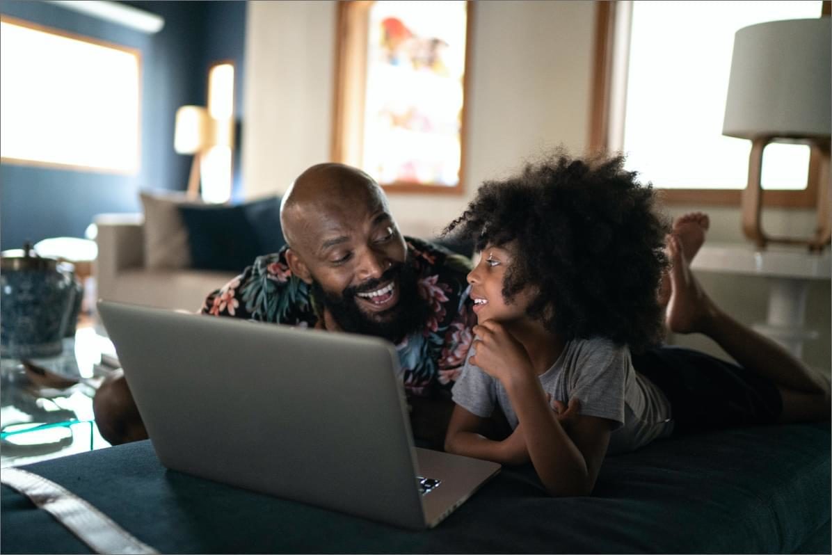Father and daughter look at laptop screen together