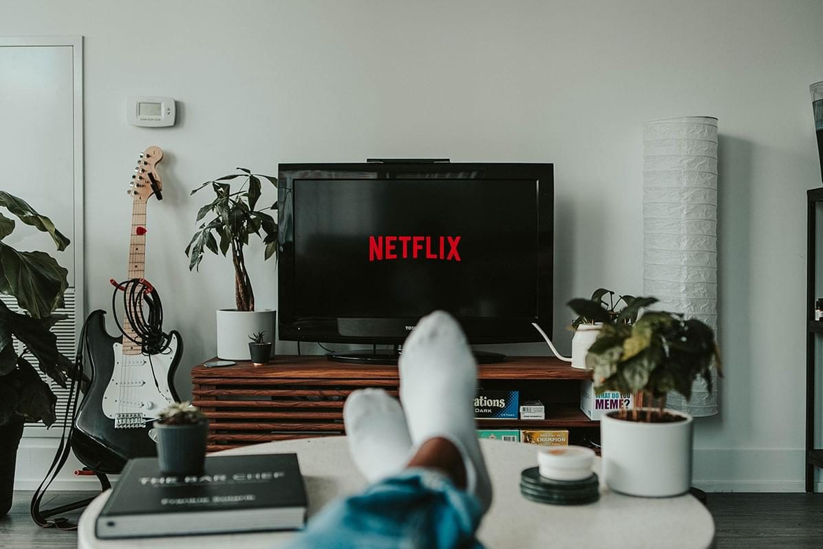 Feet propped up on coffee table with tv showing netflix logo